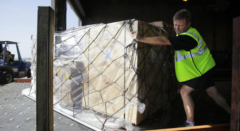 FILE- In this July 16, 2010, file photo, Mark Wilson pushes air cargo cleared for shipment to Santiago, Chile, at the American Airline cargo processing warehouse at Dallas-Fort Worth International Airport in Grapevine, Texas. U.S. authorities are requirin