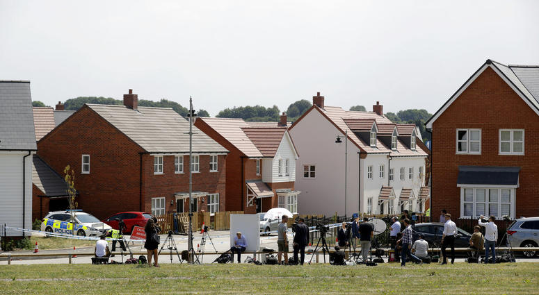 Members of the media stand outside a police cordon stopping people seeing a property shielded from view, around to the left out the picture, that police have been guarding in Amesbury, England, Thursday, July 5, 2018. British officials were seeking clues