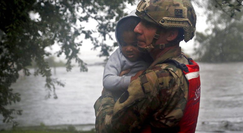 Rescue team member Sgt. Nick Muhar, from the North Carolina National Guard 1/120th battalion, evacuates a young child as the rising floodwaters from Hurricane Florence threatens his home in New Bern, N.C., on Friday, Sept. 14, 2018