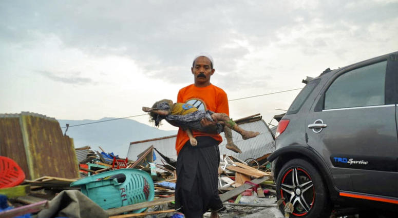 A man carries the body of a child who was killed in the tsunami in Palu, Central Sulawesi, Indonesia, Saturday, Sept. 29, 2018.