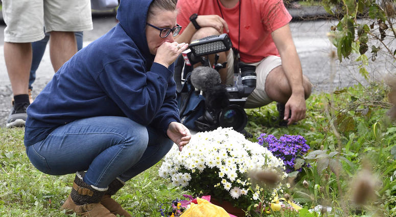 Woman knelling at make-shift memorial