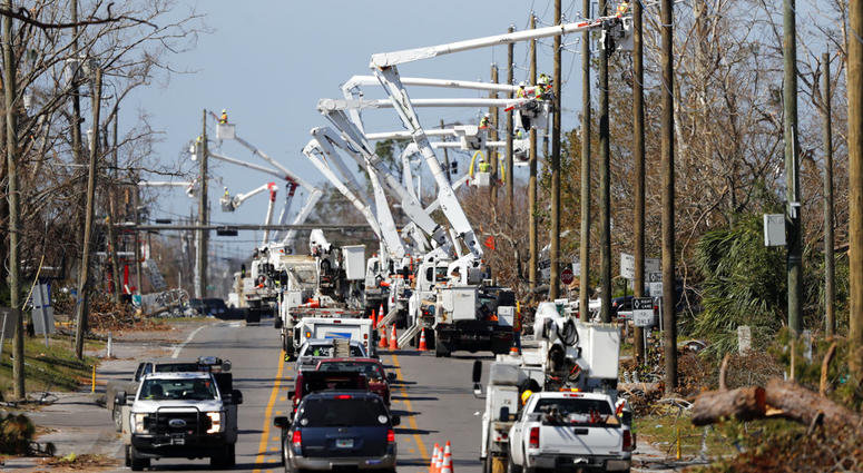 In this Thursday, Oct. 18, 2018 photo, utility crews set up new poles and utility wires in the aftermath of Hurricane Michael in Panama City, Fla