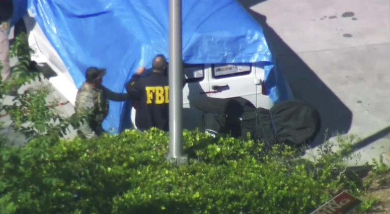 In this frame grab from video provided by WPLG-TV, FBI agents cover a van parked in Plantation, Fla., on Friday, Oct. 26, 2018. (WPLG-TV via AP)
