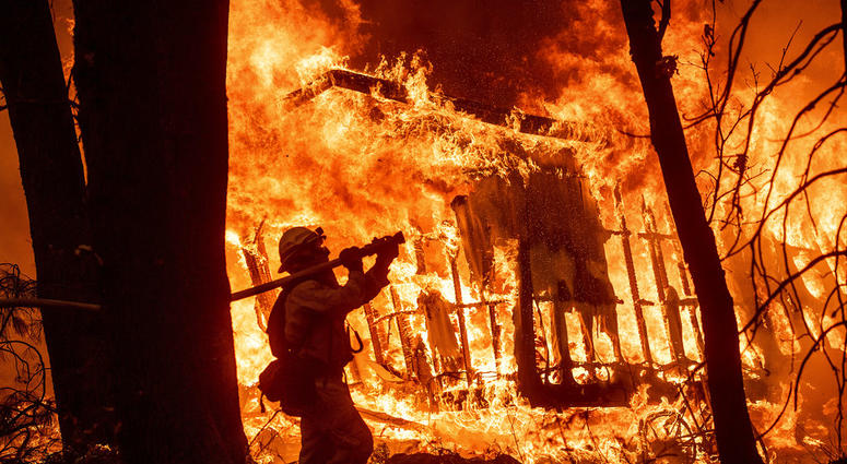 Firefighters work to keep flames from spreading through the Shadowbrook apartment complex as a wildfire burns through Paradise, Calif., on Friday, Nov. 9, 2018.