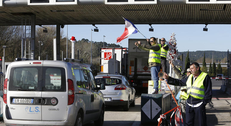 Demonstrators wearing yellow vests open the toll gates on a motorway near Aix-en-Provence, southeastern France, Tuesday, Dec. 4, 2018.
