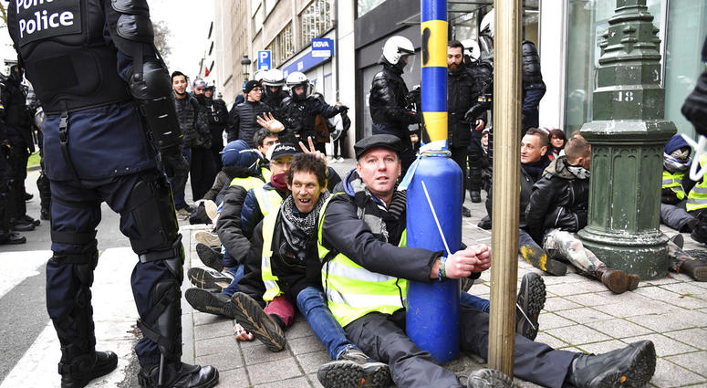 A police stands by as protestors are detained during a demonstration in Brussels, Saturday, Dec. 8, 2018.