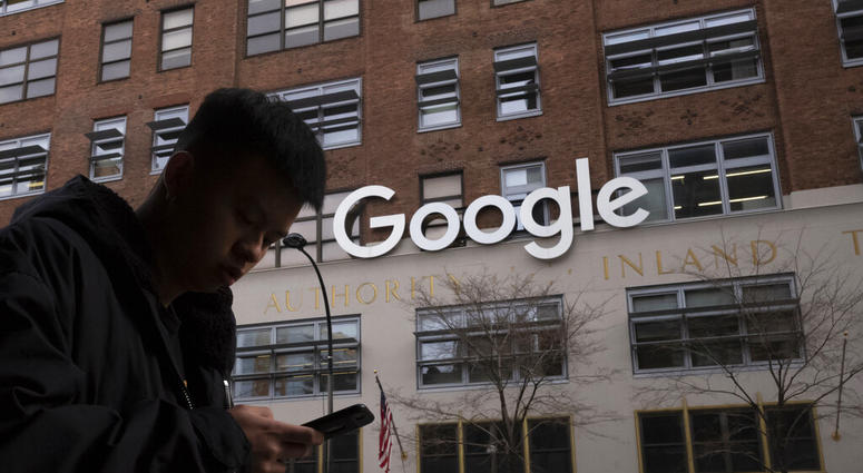 In this Dec. 17, 2018, file photo, a man using a mobile phone walks past Google offices in New York. (AP Photo/Mark Lennihan, File)