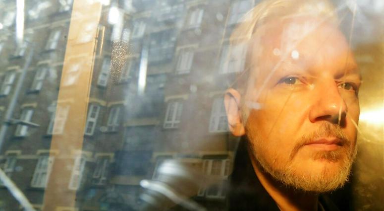 FILE - In this Wednesday May 1, 2019 file photo, buildings are reflected in the window as WikiLeaks founder Julian Assange is taken from court, where he appeared on charges of jumping British bail seven years ago, in London. Swedish prosecutors plan to de