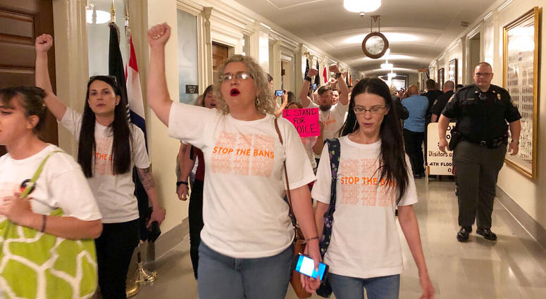 Protesters march through the halls of the Missouri Capitol outside the House chamber on Friday, May 17, 2019, in Jefferson City, Missouri, in opposition to legislation prohibiting abortions at eight weeks of pregnancy. (AP Photo/David A. Lieb)