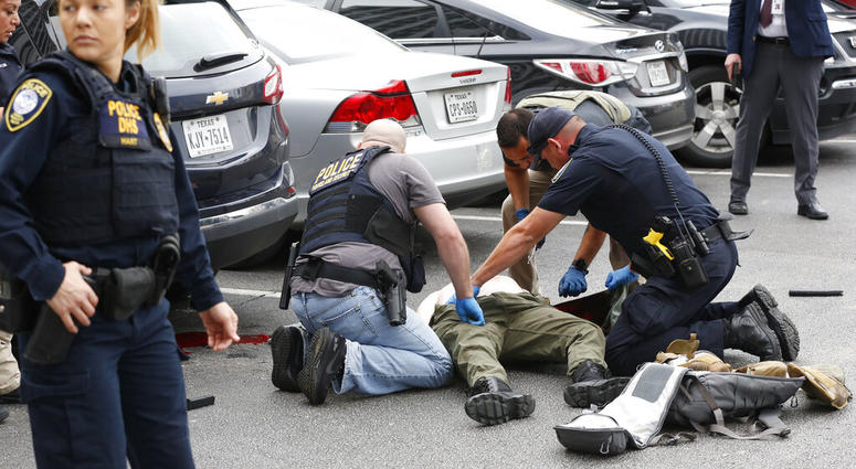 Law enforcement officers attend to an injured shooter in a parking lot after he fired shots at the Earle Cabell Federal Building in downtown Dallas, Monday, June 17, 2019. (Tom Fox/The Dallas Morning News)