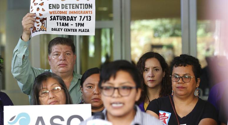 Demonstrators hold placards as Rey Wences, organizer at Organized Communities Against Deportations (OCAD) addresses reporters outside the U.S. Citizenship and Immigration Services offices in Chicago, Thursday, July 11, 2019. (AP Photo/Amr Alfiky)