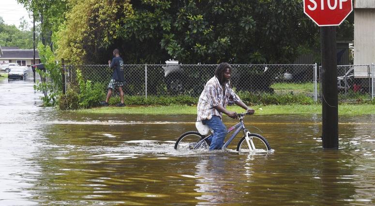 A man tries to bike through the flooding from the rains of storm Barry on LA Hwy 675 in New Iberia, La., Sunday, July 14, 2019. (Henrietta Wildsmith/The Shreveport Times via AP)