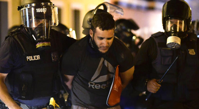 Police arrest a demonstrator during clashes demand the resignation of Gov. Ricardo Rossello in San Juan, Puerto Rico, Monday, July 22, 2019. Protesters are demanding Gov. Ricardo Rossello step down following the leak of an offensive, obscenity-laden onlin