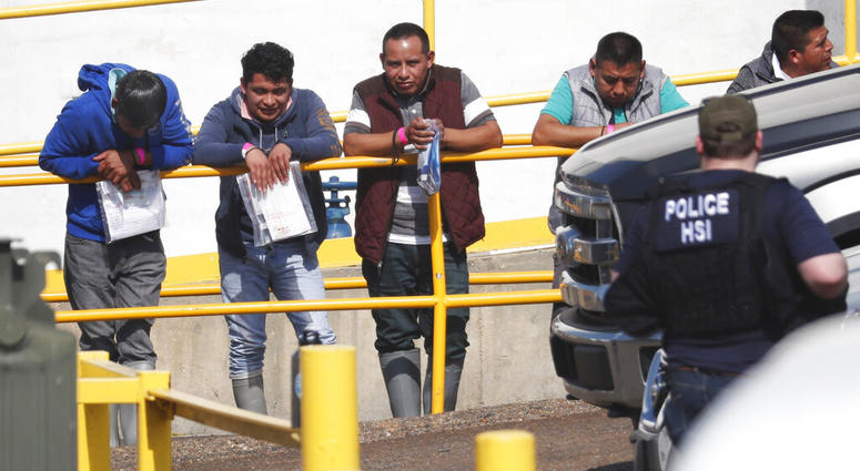 Handcuffed workers await transportation to a processing center following a raid by U.S. immigration officials at Koch Foods Inc., plant in Morton, Miss. (AP Photo/Rogelio V. Solis)