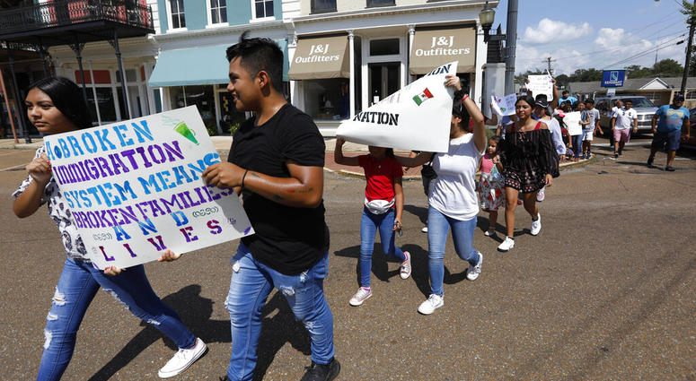 In this Aug. 11, 2019 photo, children of mainly Latino immigrant parents hold signs in support of them and those individuals picked up during an immigration raid at a food processing plant in Canton, Miss. (AP Photo/Rogelio V. Solis)