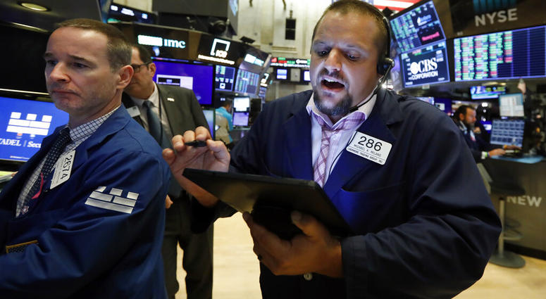 FILE - In this Aug. 19, 2019, file photo specialist Stephen Naughton, left, and trader Michael Milano work on the floor of the New York Stock Exchange. Stocks are opening slightly lower on Wall Street on Tuesday, Aug. 20, as major U.S. indexes give back a