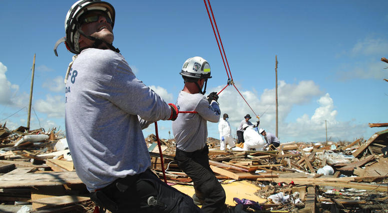 Members of the fire rescue team Task Force 8, from Gainesville, Florida, help remove a body one week after Hurricane Dorian hit The Mudd neighborhood in the Marsh Harbor area of Abaco Island, Bahamas, Monday, Sept. 9, 2019.