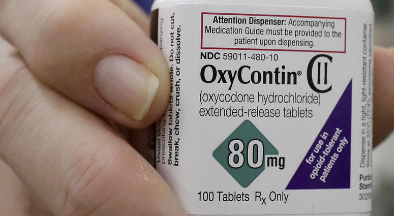 In this April 2, 2018, file photo, a pharmacist in San Francisco poses for photos holding a bottle of OxyContin. (AP Photo/Jeff Chiu, File)