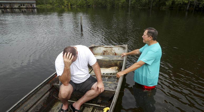 Stephen Gilbert, left, and his father-in-law sit in front of their flooded property on Friday, Sept. 20, 2019, in the Mauriceville, Texas, area.