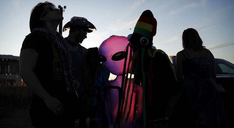 People stand around an inflatable alien at an entrance to the Nevada Test and Training Range near Area 51, Friday, Sept. 20, 2019, near Rachel, Nev. People came to visit the gate inspired by the "Storm Area 51" internet hoax.
