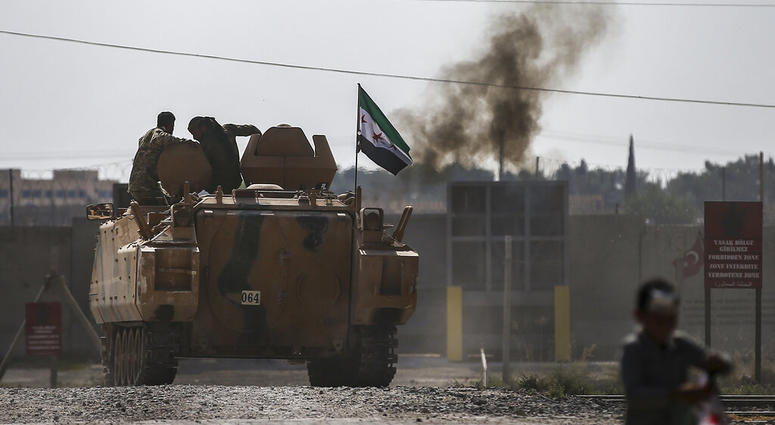 Turkish-backed Syrian opposition fighters on an armoured personnel carrier drive to cross the border into Syria, in Akcakale, Sanliurfa province, southeastern Turkey, Friday, Oct. 18, 2019. (AP Photo/Emrah Gurel)