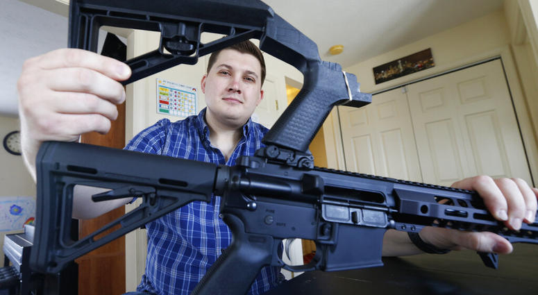 In this March 15, 2019 photo, Ryan Liskey displays a bump stock on top of his AR-15 at his home in Harrisonburg, Va. The ban on bump stocks is just a few days away and owners of the devices like Liskey are wondering what to do. (AP Photo/Steve Helber)