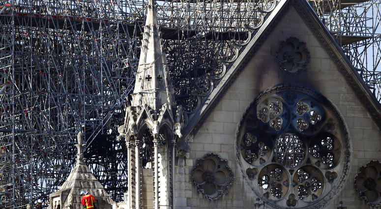 A fire fighter makes his way on a balcony of Notre Dame cathedral Wednesday, April 17, 2019 in Paris. French President Emmanuel Macron ratcheted up the pressure by setting a five-year deadline to restore the 12th-century landmark. (AP Photo/Francois Mori)
