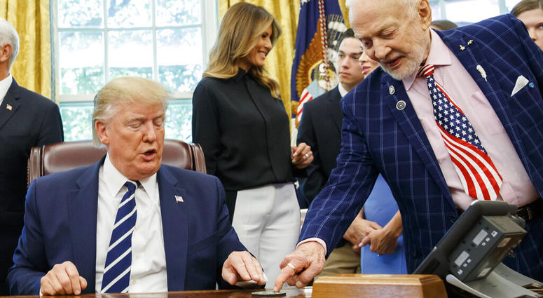 President Donald Trump receives a gift from Apollo 11 astronaut Buzz Aldrin, with first lady Melania Trump, during a photo opportunity commemorating the 50th anniversary of the Apollo 11 moon landing in the Oval Office. (AP Photo/Alex Brandon)