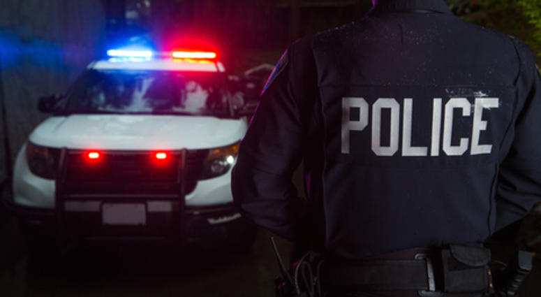 A police officer standing near his car with the light on