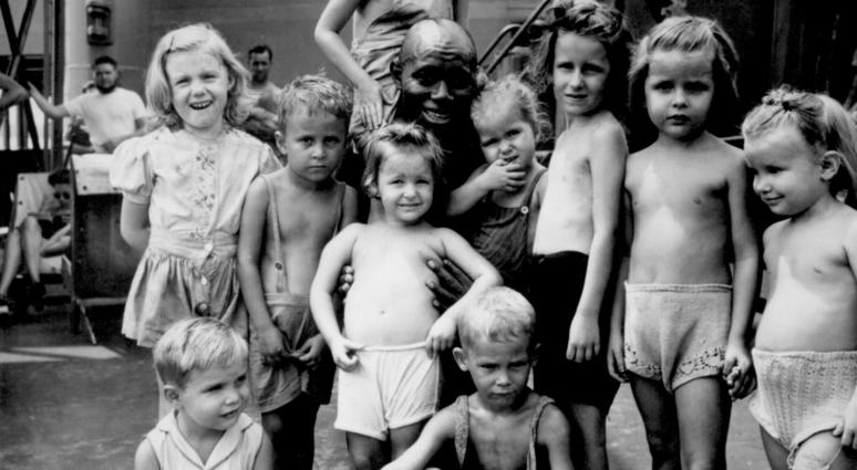 April 1945 4. Children aboard the SS Jean Lafitte, bound for the States with internees freed from a Japanese internment camp in the Philippines, gather around Pendleton Thompson. Thompson volunteered as cook in the camp where they were interned.