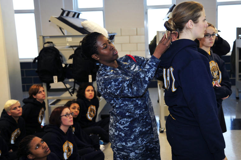 Chief Logistics Specialist Natali Philip (left), a recruit division commander (RDC), uses a ruler to measure the hair of Seaman Recruit Briana Cochems, from Los Angeles, to show proper hair grooming standards to new recruits at Recruit Training Command