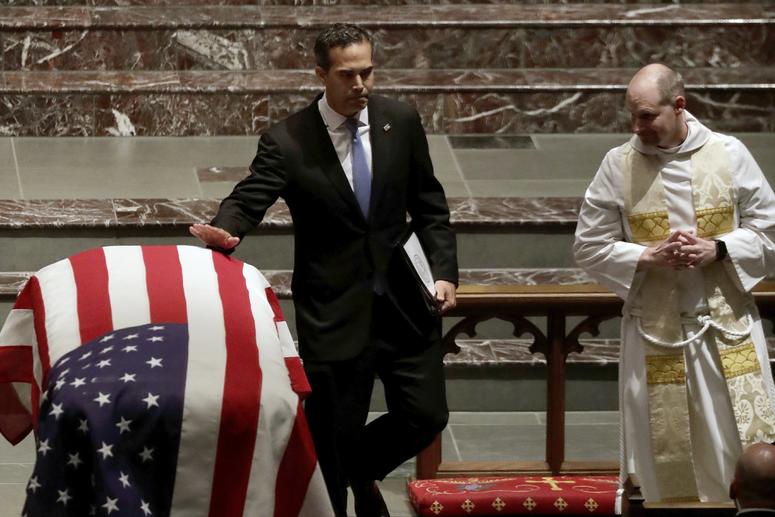 George P. Bush touches the flag-draped casket of his grandfather, after delivering an eulogy at the funeral of former President George H.W. Bush in Houston, Texas.