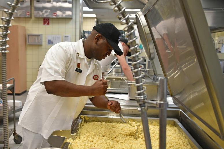 U.S. Army Sgt. Kareem Garrett, a culinary specialist with Fury Battery, 4th Battalion, 319th Airborne Field Artillery Regiment, 173rd Airborne Brigade, cooks macaroni and cheese at the Tower Barracks Dining Facility, Grafenwoehr, Germany, May 3, 2018.