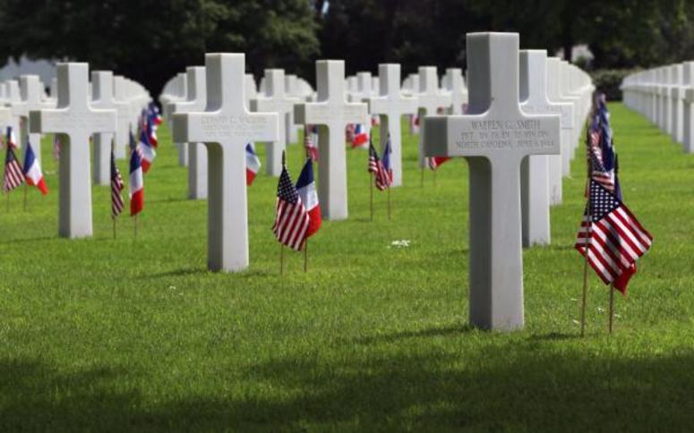 The tombstone of U.S. Army Pvt. Warren G. Smith, right, a paratrooper assigned to the 319th Field Artillery Battalion, 82nd Airborne Division, at the Normandy American Cemetery and Memorial on May 28, 2018, in Colleville-sur-Mer, France.