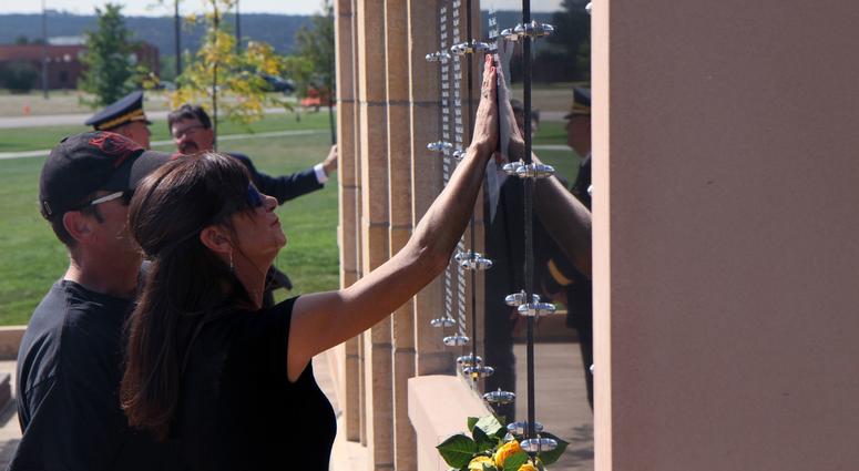 The mother of a fallen South Dakota National Guard soldier reaches out to touch her son’s name on the wall of the new memorial plaza