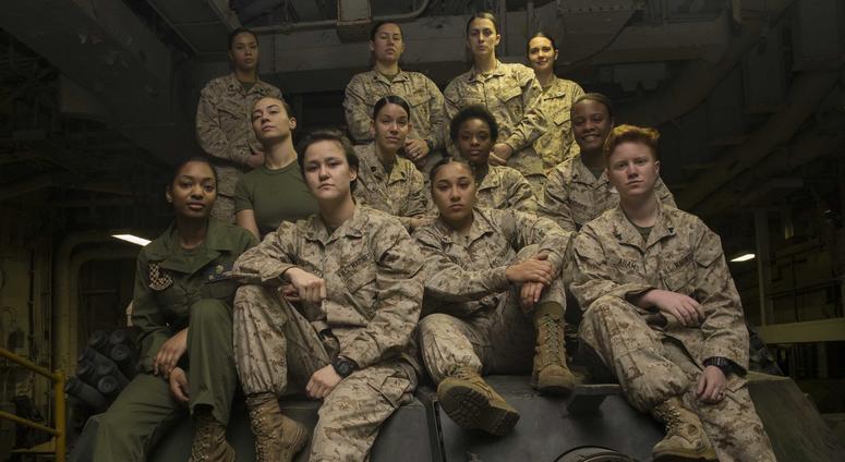 Female Engagement Team Marines pose atop an M1A1 Abrams Main Battle Tank turret after completing training