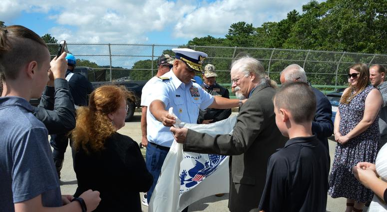 Coast Guard Adm. Andy Tiongson presents Stephen and Bradley Finch with the Coast Guard Ensign