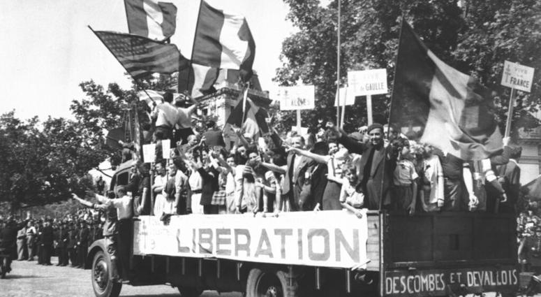 In this Aug. 28, 1944 file photo, a truck load of Parisians waving flags and carrying Vive De Gaulle banners drives through the streets