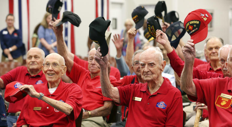 World War II veterans salute with their caps as they pose for a photograph after a ceremony at Joint Base San Antonio-Fort Sam Houston