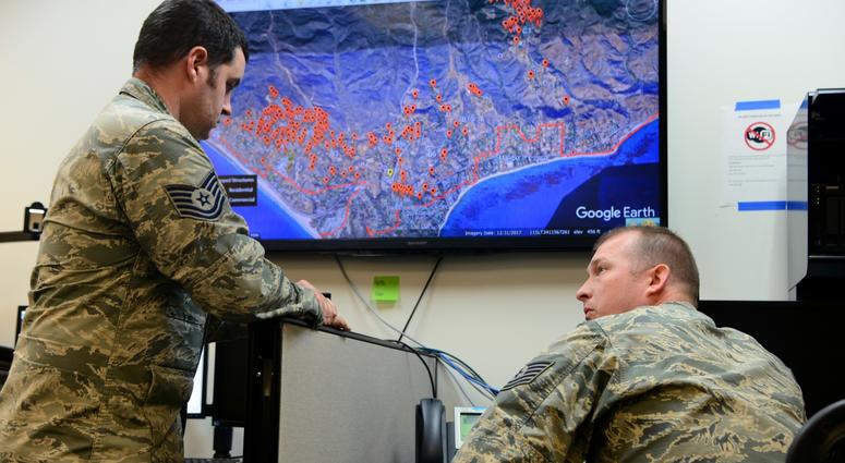 Tech. Sgt. Roy Davis and Staff Sgt. Matt Lemaire, 234th Intelligence Squadron intelligence analysts, sit on a conference call with various civilian and military agencies regarding the California wildfires Nov. 14, 2018, at Beale Air Force Base, Calif. The
