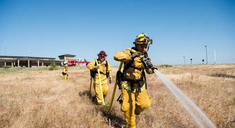 9th Civil Engineer Squadron firefighters use a charged hose line to attack a mock wildfire at Beale Air Force Base, California June 8, 2018. Grassland wildfires can spread at speeds upwards of 14 mph when aided by local wind speeds.