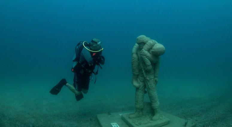 A diver comes face-to-face with one of 12 life-size statues of members of the Armed Forces that make up the Circle of Heroes underwater veterans memorial. DiverStatue