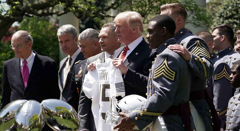 U.S. President Donald Trump is presented with a jersey by team captain Ahmad Bradshaw (R) during an event with the Army Black Knights football team from the U.S. Military Academy May 1, 2018 in the Rose Garden at the White House in Washington, D.C. TrumpMilitaryAcademy