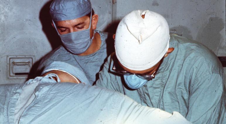 On July 25, 1969, Army Surgeons Mo Levine (center) and Al Agudelo (right) operate on Specialist 5 John Fogle— shortly after John was wounded while serving as a helicopter door gunner near Phu Bai, Vietnam. Medic Mickey Caskey (foreground) assists.