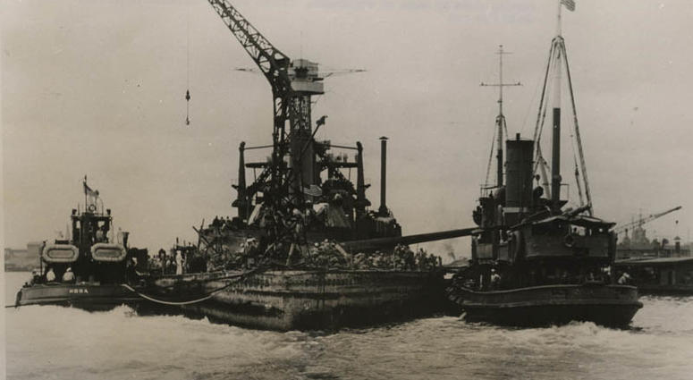 Pearl Harbor Bombing - "USS California - the 32,600-ton battleship, USS California is shown being towed to dry dock at Pearl Harbor T.H. This ship was raised from her shallow resting place by means of cofferdams" (Official U.S. Navy Photo from OWI)