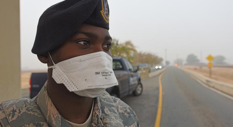 Senior Amn LeShawn Nash, 9th Security Forces Squadron, dons his N95 protective mask as he stands guard at the gate Nov. 15, 2018, at Beale Air Force Base, California. The Air Quality Index at Beale is currently hazardous because of the smoke caused by the
