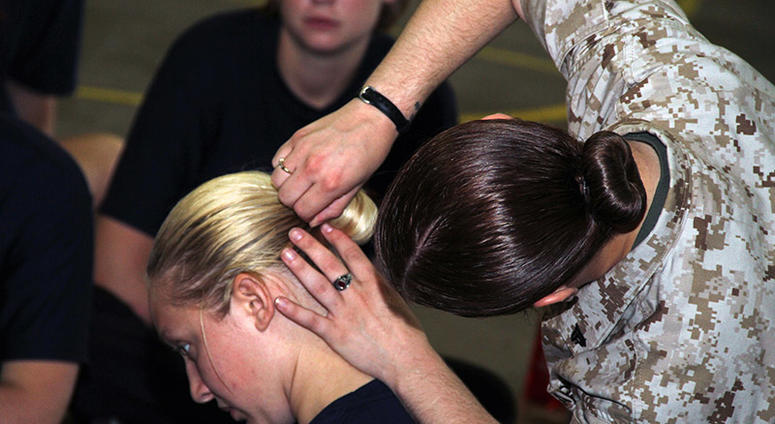 Rachael Weatherford, a 20-year-old graduate of Minnewaska High School, watches Cpl. Rebecca Carlson, 22, from Hastings, Minn., put up Sarah Belden's hair with a sock-bun while attending a Recruiting Station Twin Cities female pool function June 24-25. Wom