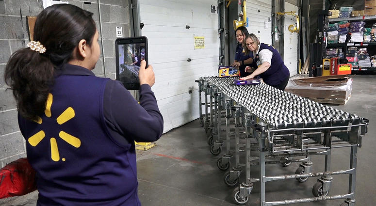 Wal-Mart Academy students Celia Flores Lagunas, from left, Cherie Johnson and Janet Holcomb make a short video showing the product cycle at a typical Wal-Mart, including unloading new merchandise.