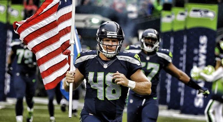 Nate Boyer leads the Seattle Seahawks onto the field carrying the American flag Nate Boyer leads the Seattle Seahawks onto the field carrying the American flag
