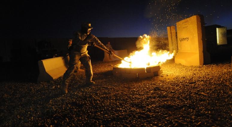 U.S. Army Sgt. 1st Class Jimmy Cunningham, of Pontotoc, Miss., assigned to the 1st of the 230th Air Cavalry Squadron, Golf Troop, 2nd Fuel and Armor Platoon, stokes a fire pit while burning documents at COP Nimer, near Sinjar, Iraq, Sept. 30 2009.